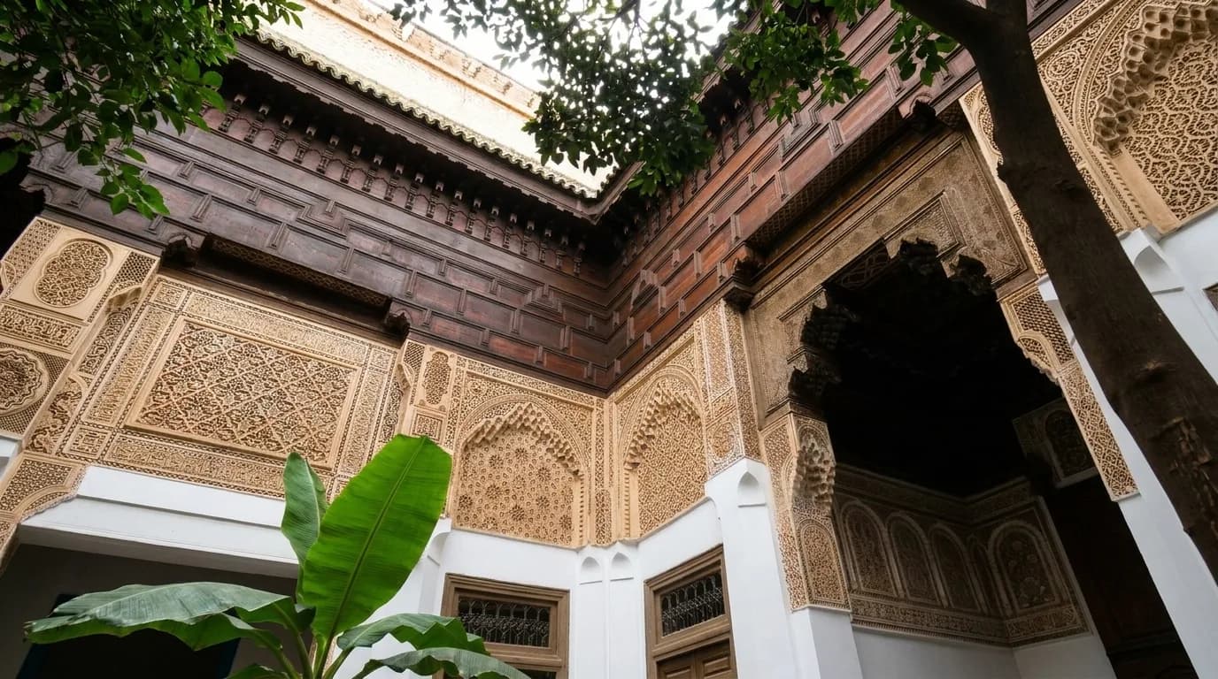 Carved cedar and stucco courtyard corner with green plants at Bahia Palace Marrakech