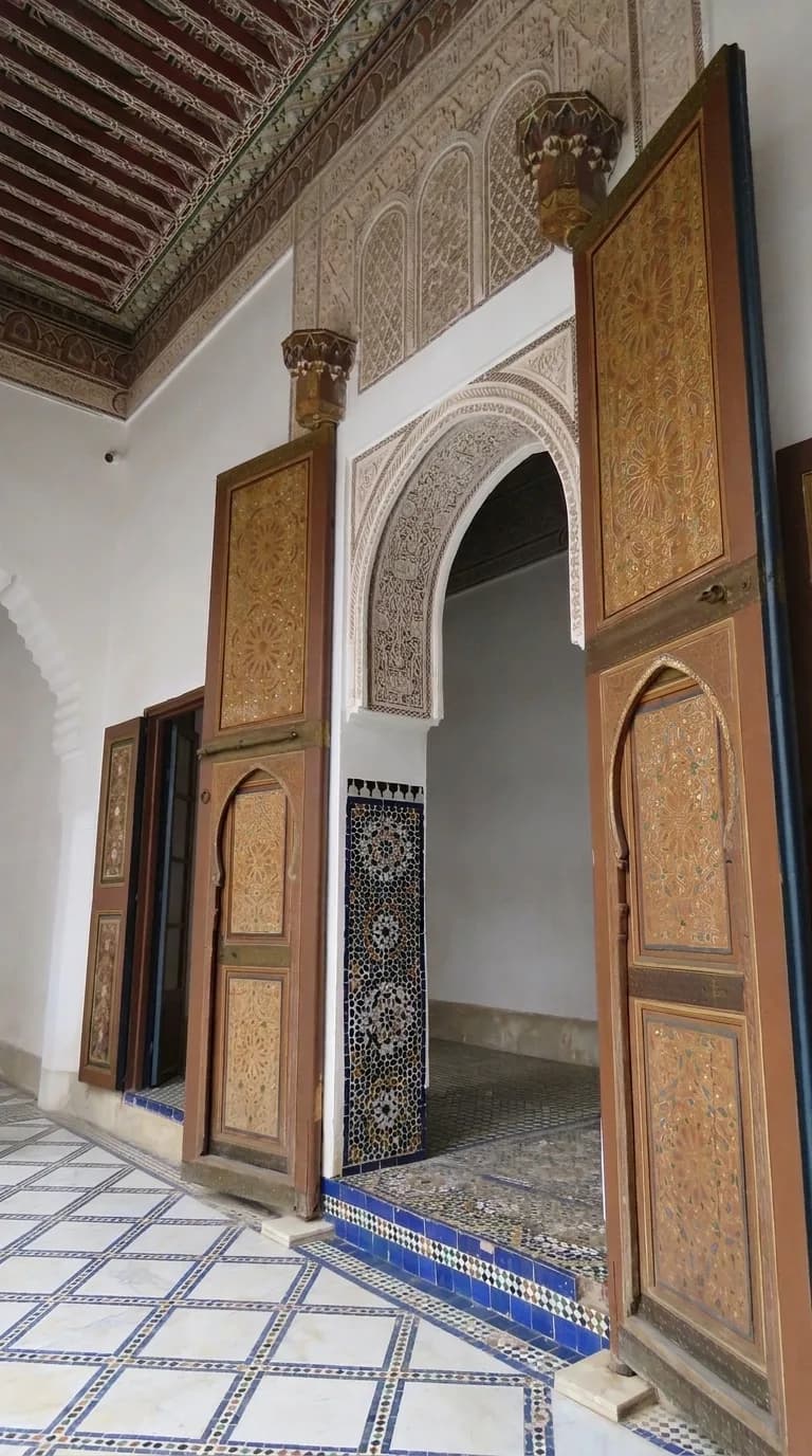 Tall carved and painted cedar doors framing an arched doorway at Bahia Palace Marrakech