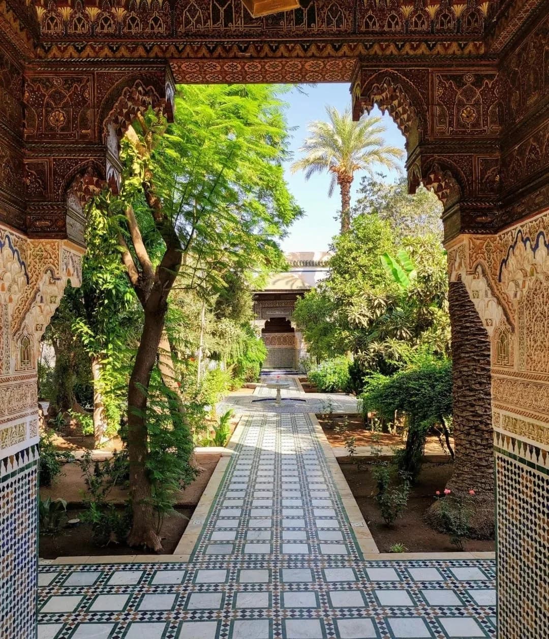 View of the palace garden and palm trees framed by a carved archway at Bahia Palace