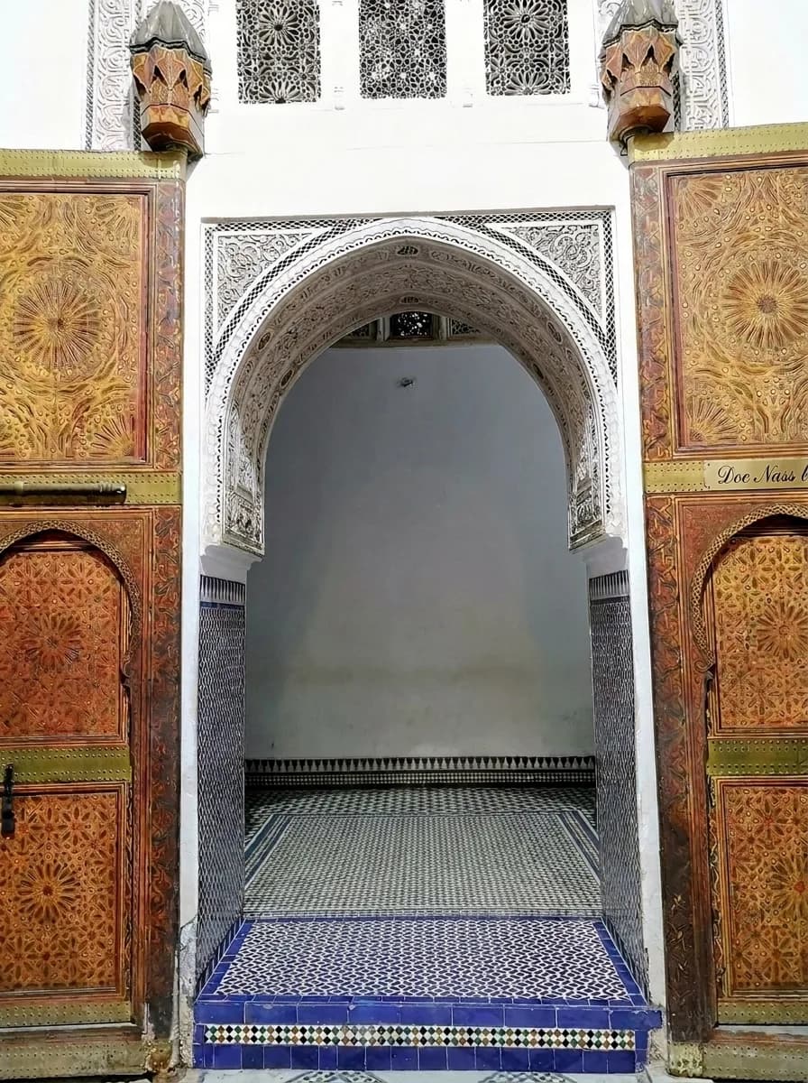 Carved stucco arch and wooden doors at the main entrance gate of Bahia Palace Marrakech
