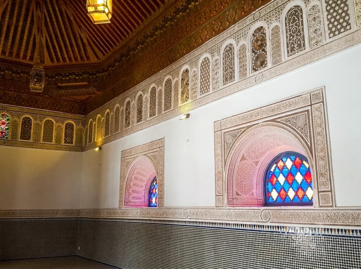Carved stucco alcoves with stained glass windows and zellige dado inside Bahia Palace
