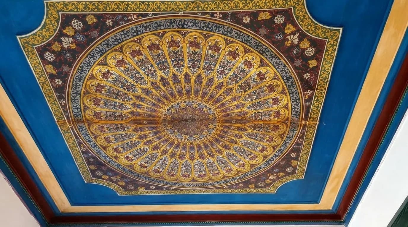 Blue and gold painted wooden ceiling with a radiating sunburst pattern at Bahia Palace