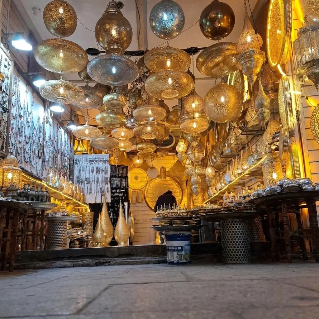 Brass and coloured glass lanterns hanging from the ceiling of a lamp shop in the Marrakech souk — Palais de la Bahia Marrakech