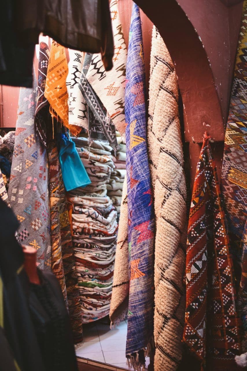 Traditional handmade Moroccan zarbia rug displayed in Marrakech souk, featuring colorful Berber patterns and authentic artisan craftsmanship — Palais de la Bahia Marrakech