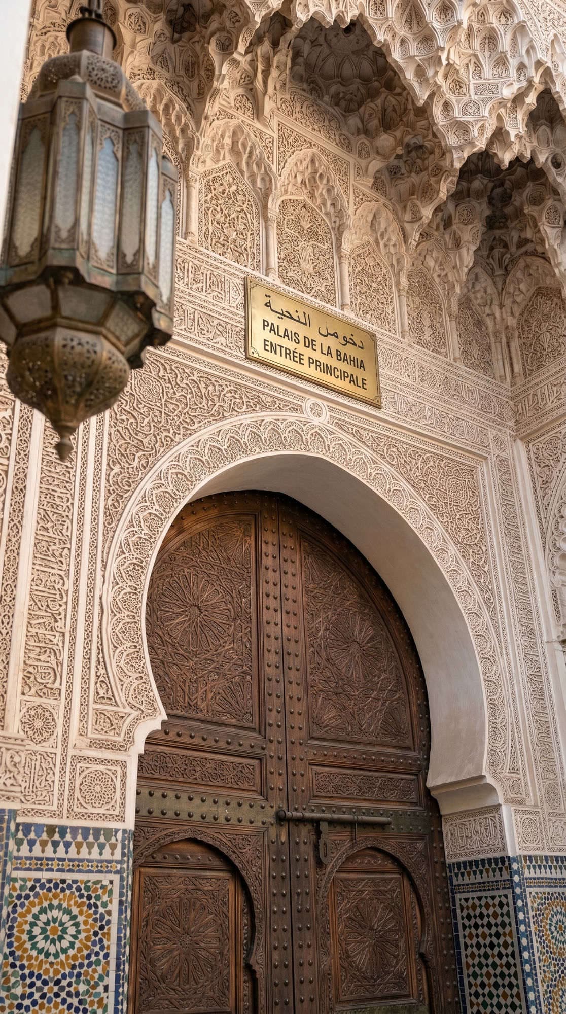 Bahia Palace main entrance sign Palais de la Bahia with ornate stucco arch and brass lantern Marrakech