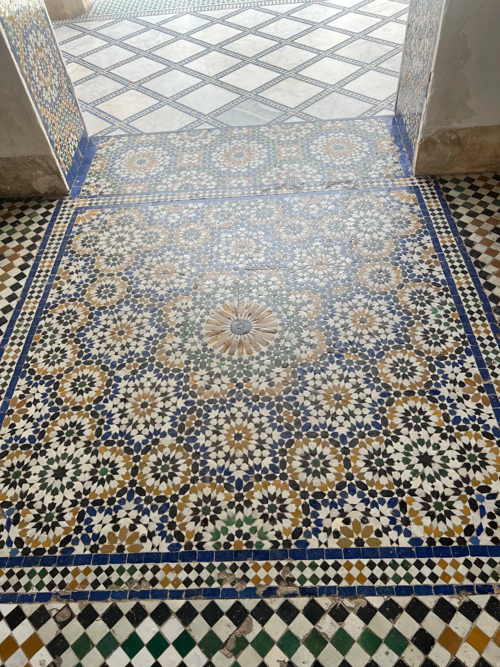 لقطة قريبة لأرضية زليج مقطوعة يدوياً بنمط نجمي هندسي في قصر الباهية بمراكش، تُظهر الحرفية المغربية في القرن التاسع عشر